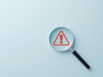 magnifying glass over exclamation mark
